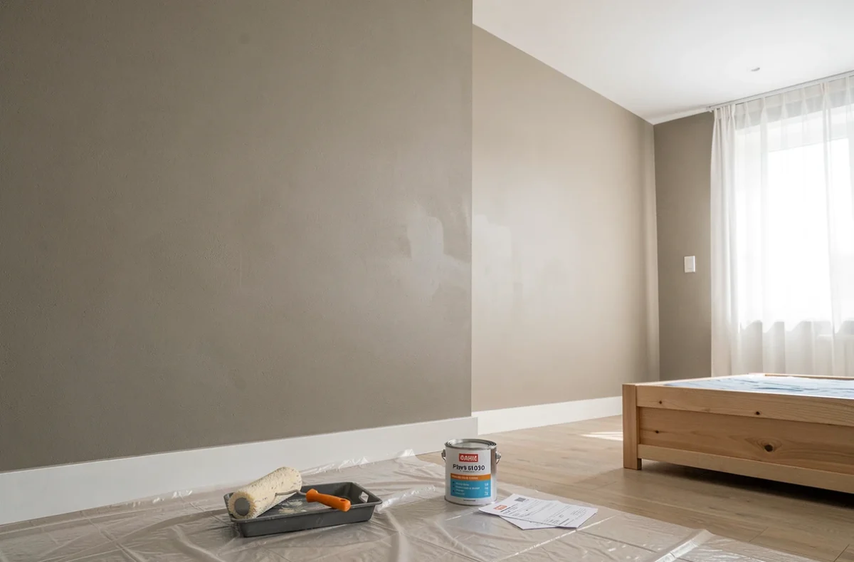 Chambre fraîchement peinte avec rouleau, bac à peinture et facture détaillant le coût de la peinture des murs et du plafond