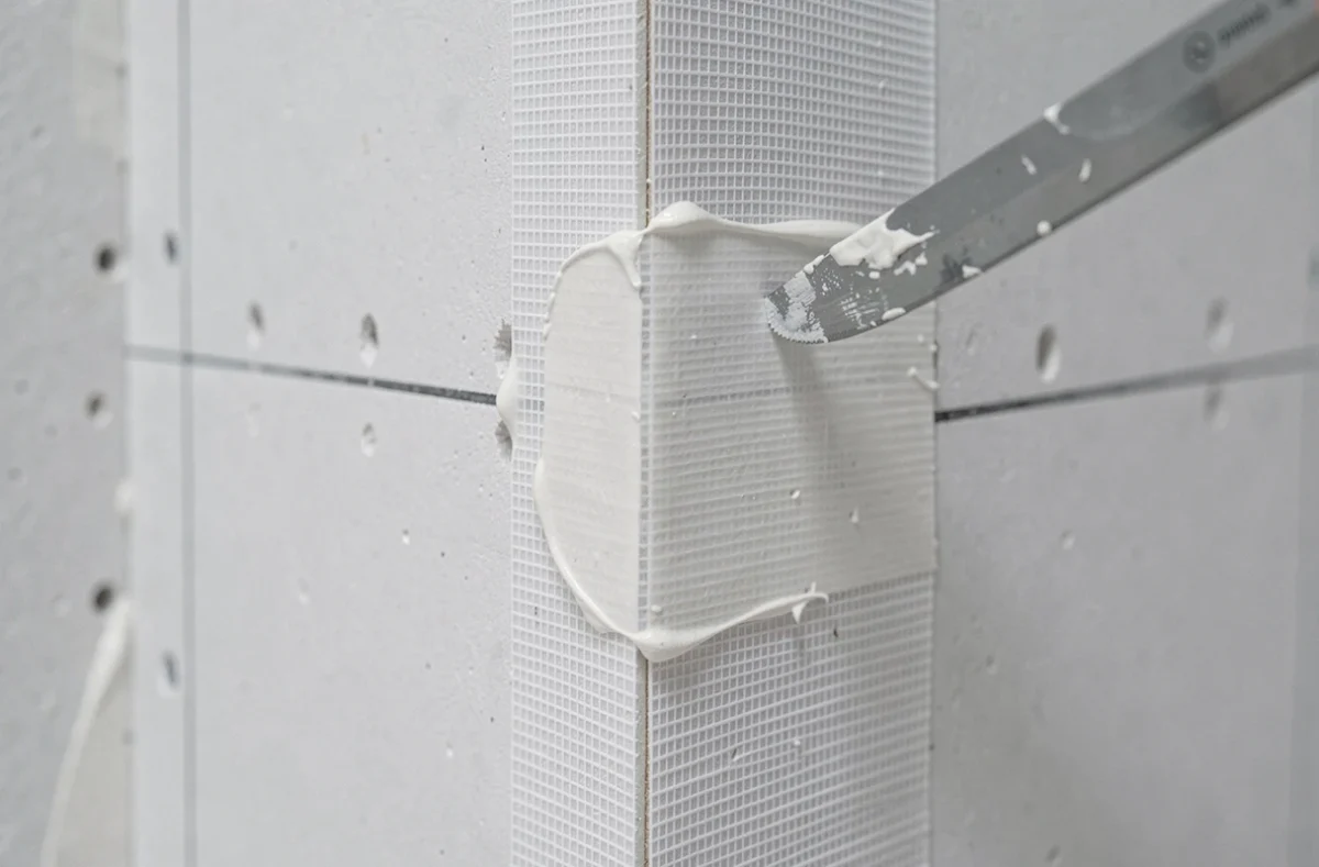 Détail d'une bande armée fibre de verre appliquée sur un joint de plaque de plâtre avec enduit de jointement