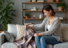 Plaid sur canapé : conseils pour bien le disposer et décorer – Astuces déco Femme arrangeant une couverture plaid dans un salon cosy