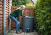 Eau de pluie pour les toilettes : est-ce possible et écologique ? Femme examinant un tank d'eau de pluie dans un jardin