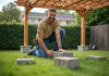 Construire une pergola sans creuser : techniques et astuces faciles à appliquer Homme souriant posant avec pergola en bois dans jardin
