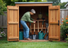 Outils de jardinage : ranger à l’extérieur sans risques ? Femme organisée dans son abri de jardin en jeans et pull vert