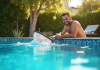Homme nettoyant la piscine avec un filet à la surface en été