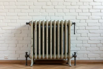 Radiateur en fonte d'occasion à colonnes ornées contre un mur en briques peintes dans un appartement haussmannien rénové