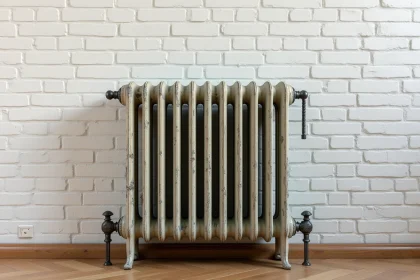 Radiateur en fonte d'occasion à colonnes ornées contre un mur en briques peintes dans un appartement haussmannien rénové